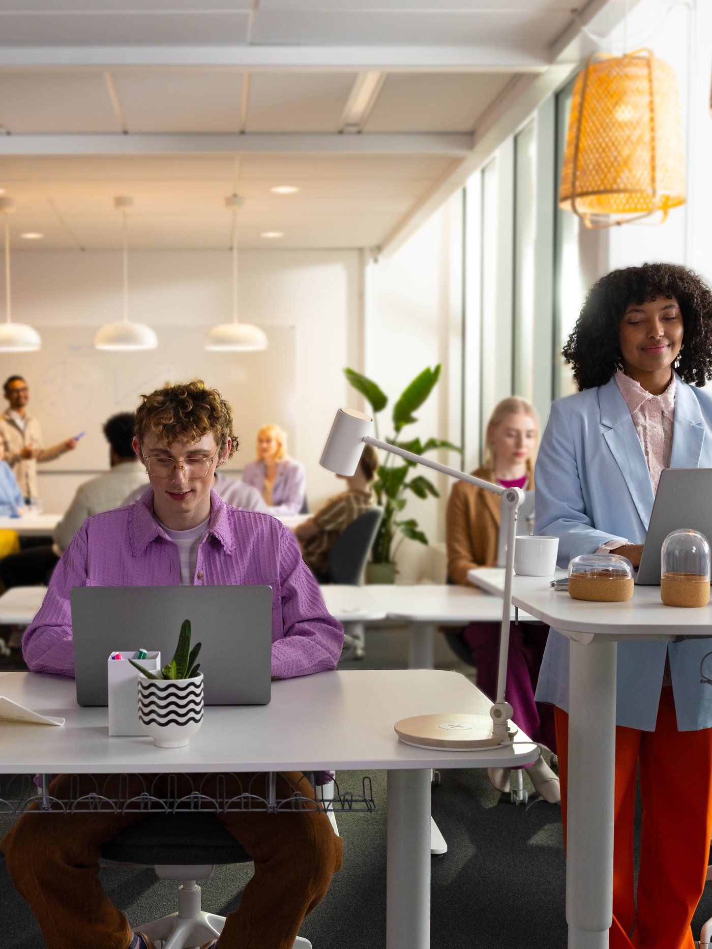 Several people are sitting or standing in front of their desks in an open-plan office.