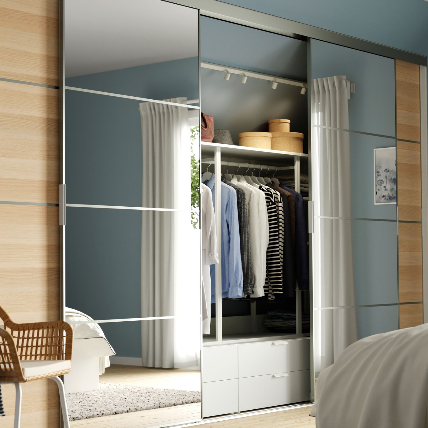 A SKYTTA sliding door solution in a bright bedroom. The doors are partly open, showing clothes and storage behind.