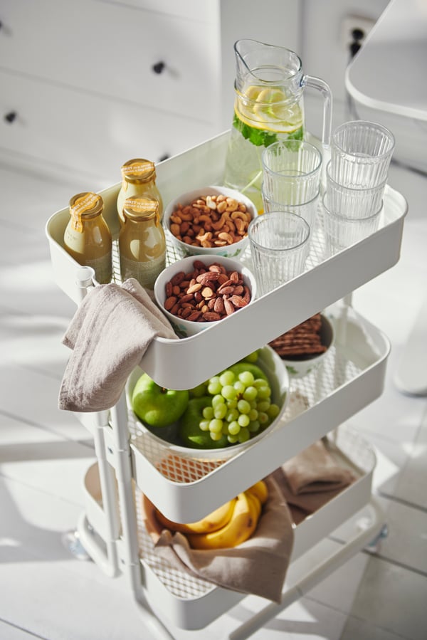 Ein RÅSKOG Servierwagen mit verschiedenen Snacks, Obst, Getränken