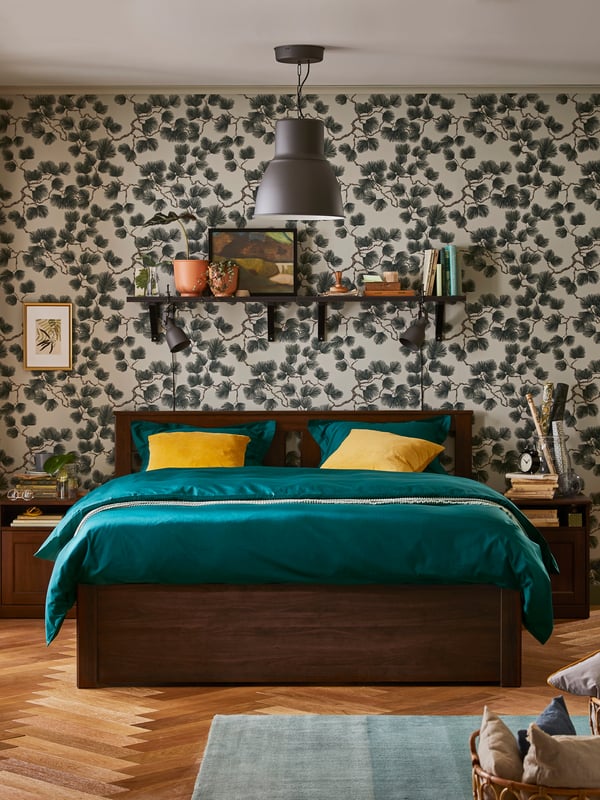 A SONGESAND bed frame with dark green sateen-woven bedding in a bedroom with a grey pendant lamp.