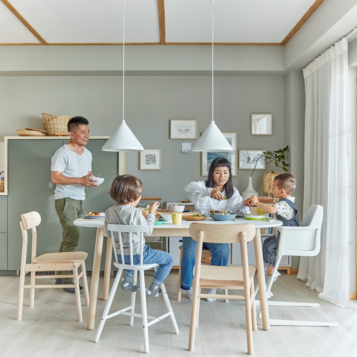 Eine Familie mit Kleinkindern, verschiedene Esszimmerstühle und ein weißer VEDBO Esstisch im Esszimmer.
