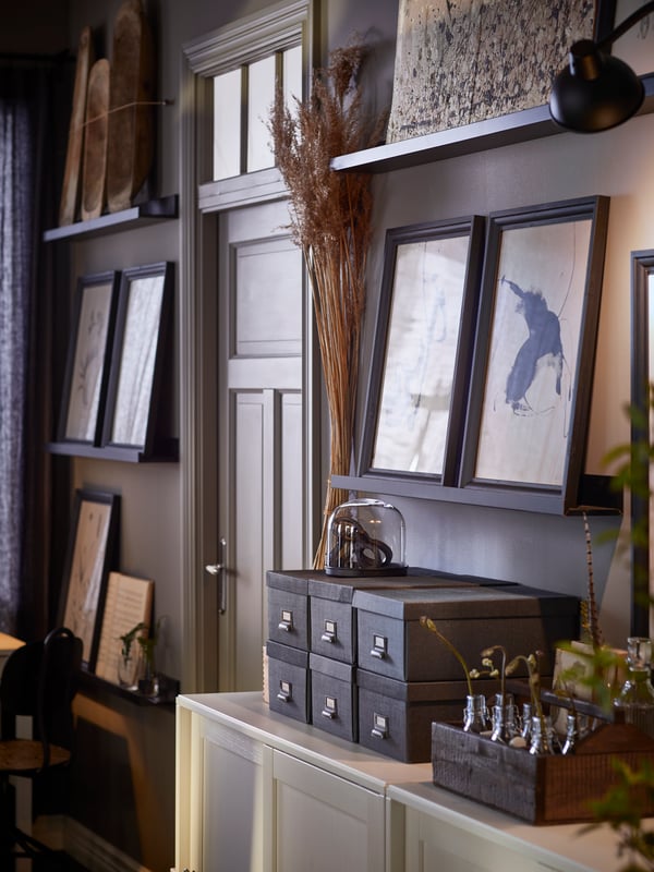 Several MOSSLANDA picture ledges with framed artworks are placed on either side of a door in a rustic farmhouse-style room.