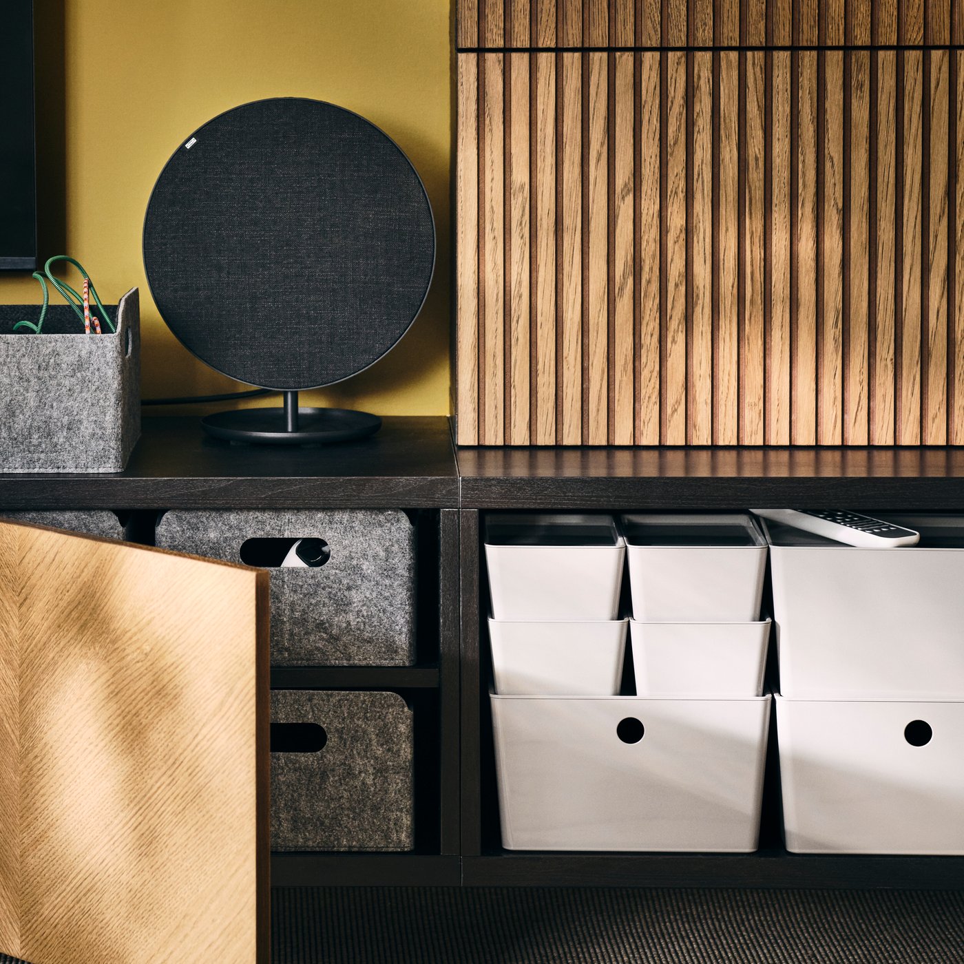 A wall-mounted BESTÅ storage combination, wood-veneer fronts open to reveal BESTÅ felt boxes and stacked white KUGGIS boxes.