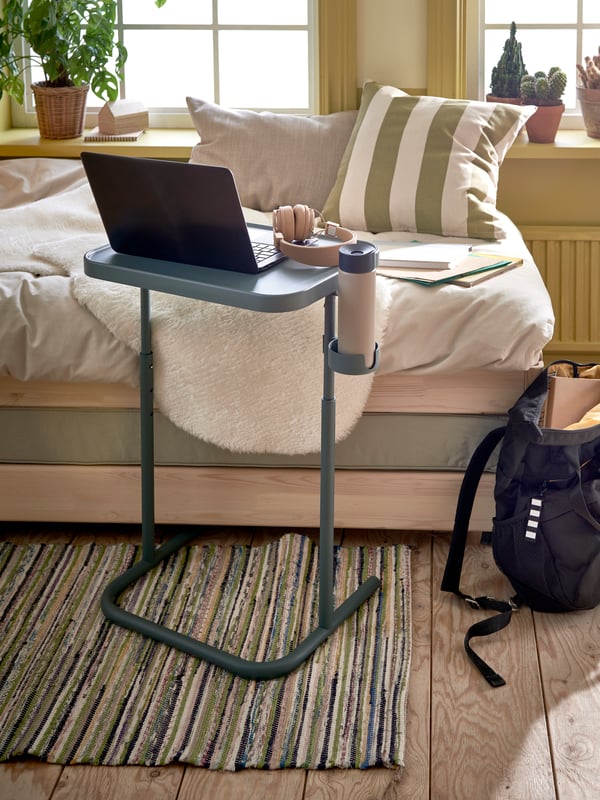 En una sala hay una daybed y delante de ella una mesa para portatil sobre un tapete hecho a mano TÅNUM .
