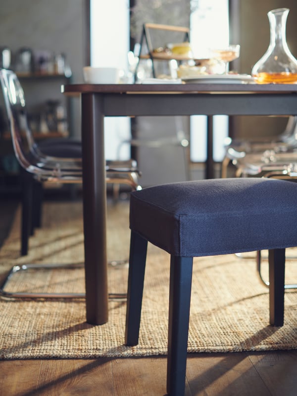 A SAKARIAS stool and TOBIAS chair by a STRANDTORP table that is set with various items of food and drink.