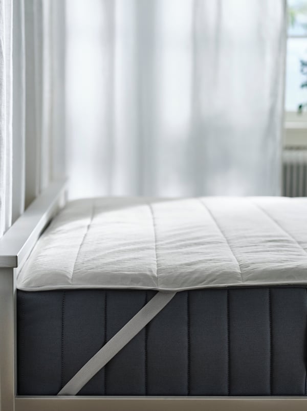 Hujung atas bagi katil HEMNES berwarna putih dengan tilam spring poket VALEVÅG padanya, dilitupi pelindung tilam ROSENVIAL.
