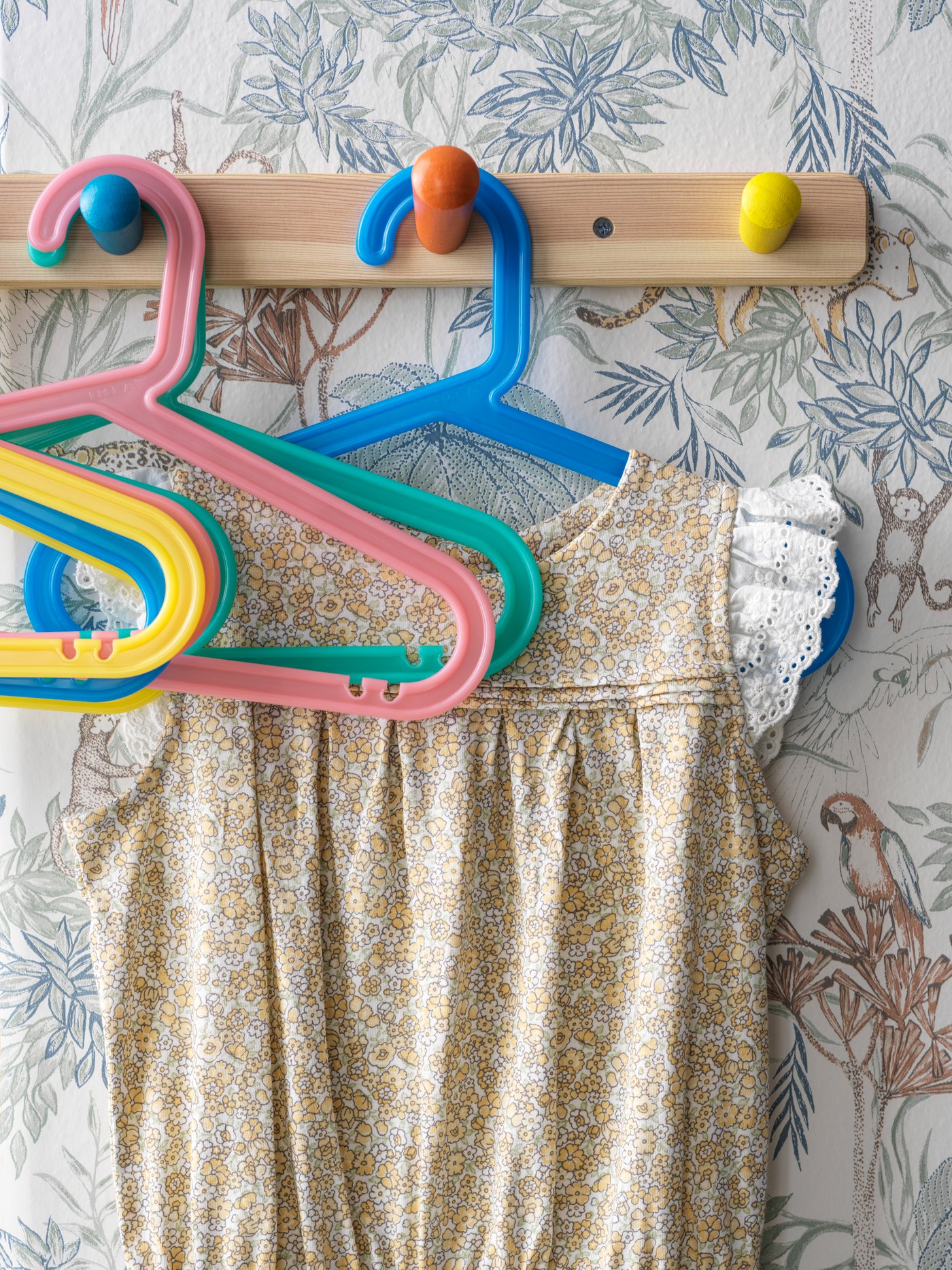 Un gancho de madera con colgadores de ropa infantiles.