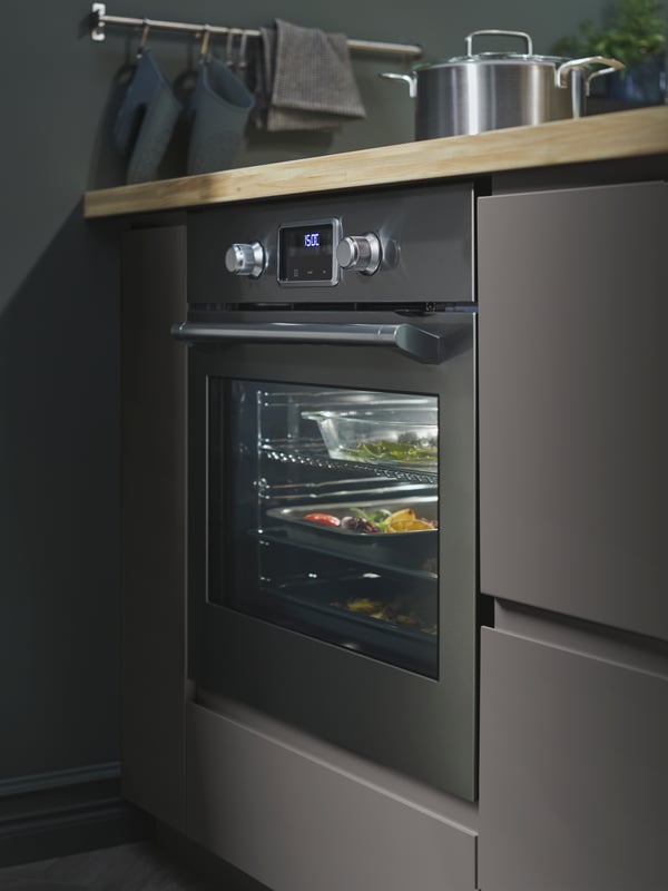 Forno SMAKSAK in acciaio inox in una cucina con frontali VOXTORP grigi.