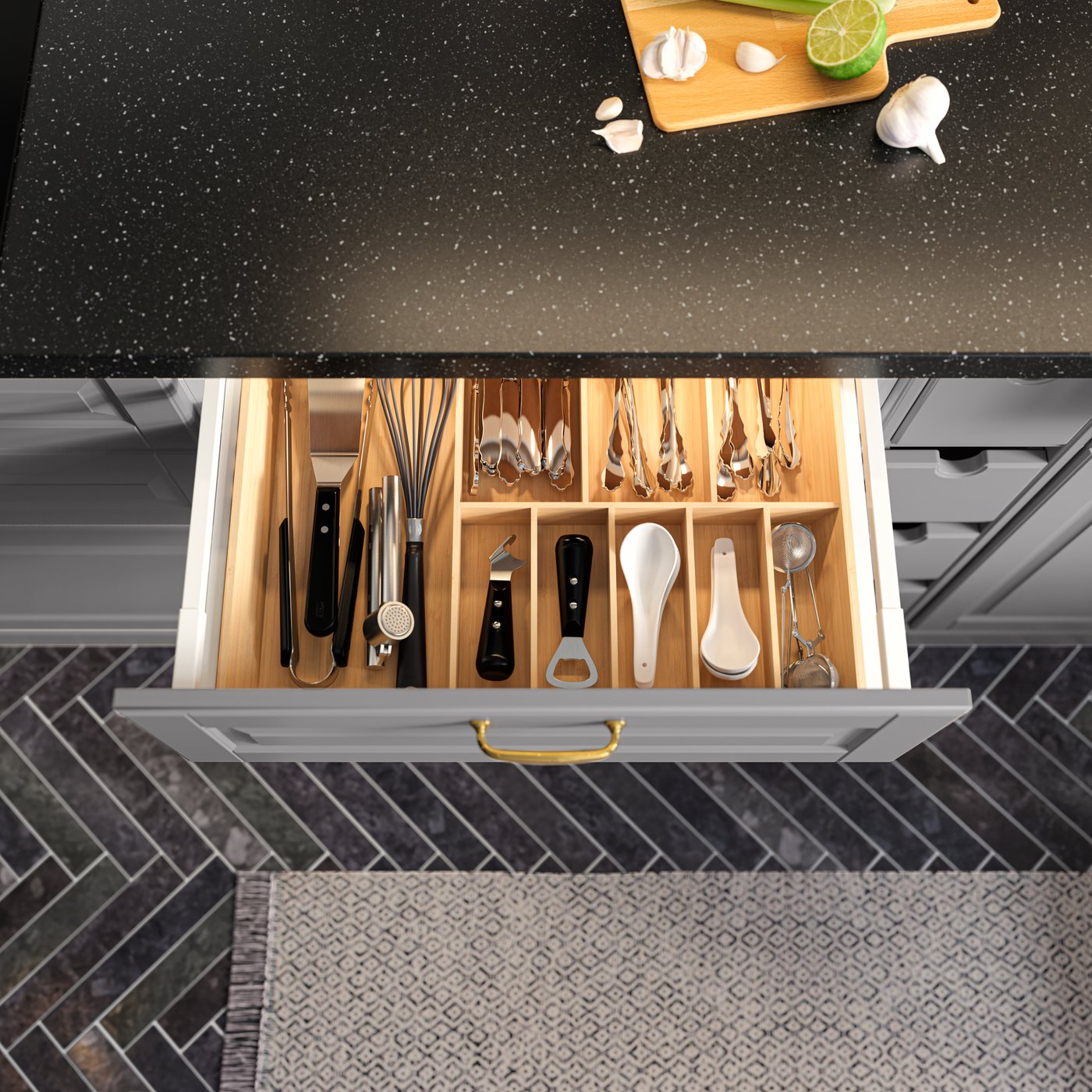 An open kitchen drawer with a bamboo cutlery tray filled with kitchen utensils