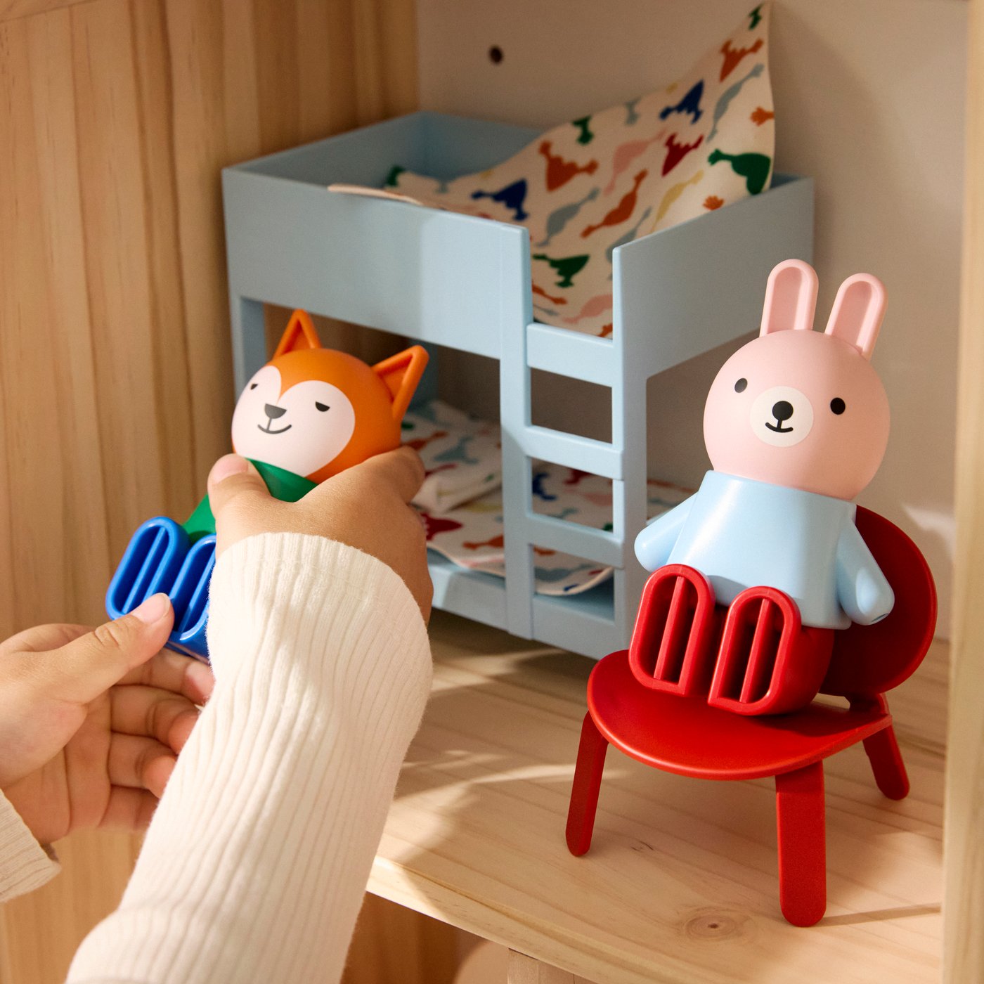 Un par de manos infantiles juega con muñecas HUSET y una casa de muñecas.