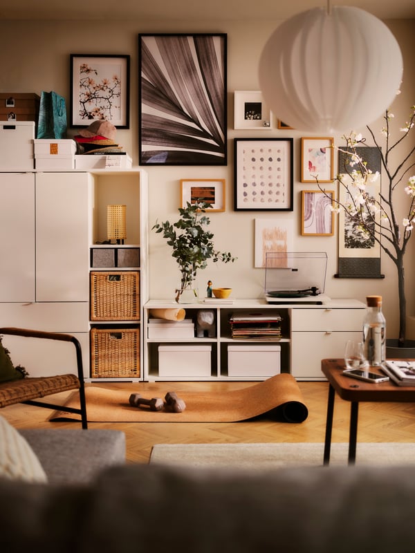 A living-room wall half-covered by a white VIHALS storage combination, the other half dotted with a cluster of framed art.