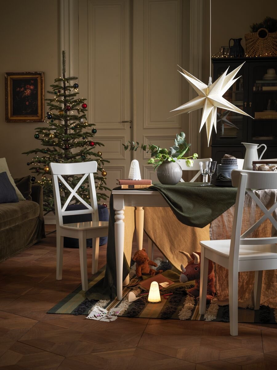 Un árbol de Navidad y una mesa de comedor en un salón festivo, con una guarida secreta llena de juguetes debajo de la mesa.