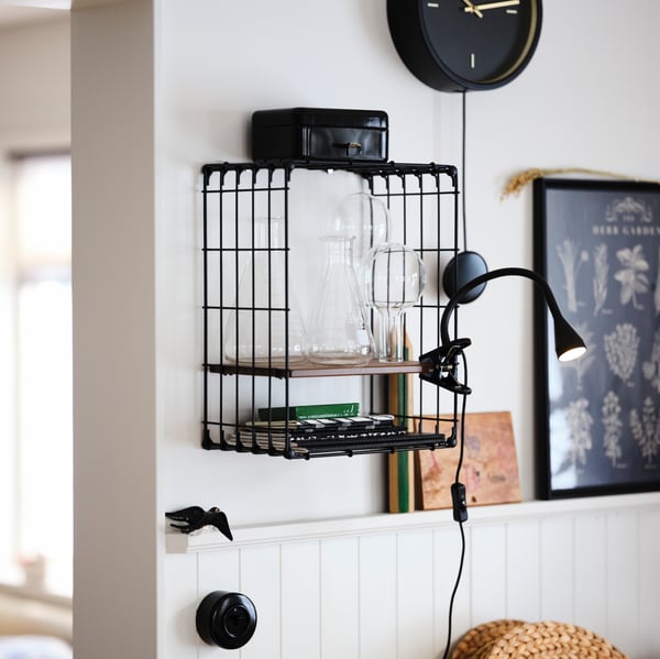 A white wall with a black/pine antique effect GULLHULT wall shelf with a black STURSK wall clock above.