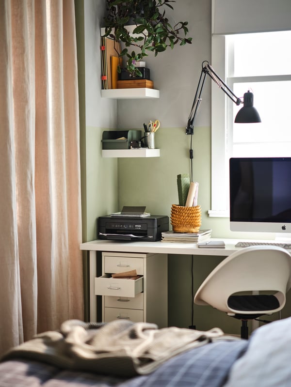 Una haitación infantil con una cama y un escritorio en la ventana. Al costado del escritorio una serie de repisas soportando decoraciones y plantas.