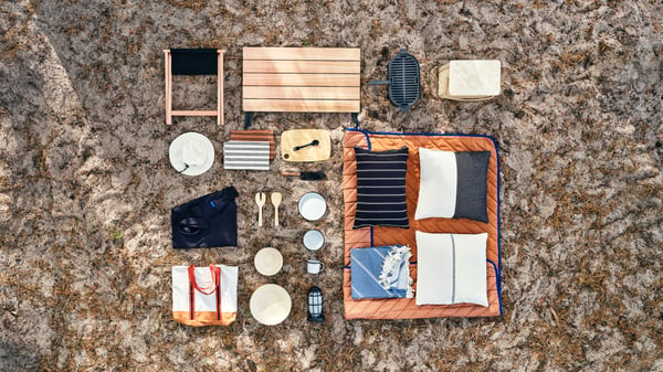 The entire SOLUPPGÅNG collection seen from above, featuring a picnic blanket, a foldable table, stool, cutlery set and cooler bag for enjoying life outdoors.