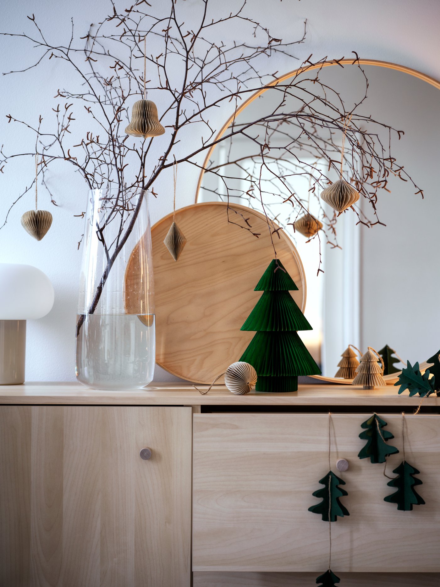 Des branches et des brindilles sont disposées dans le vase BERÄKNA. Tout est paré et décoré pour Noël sur le buffet ERSNÄS. 