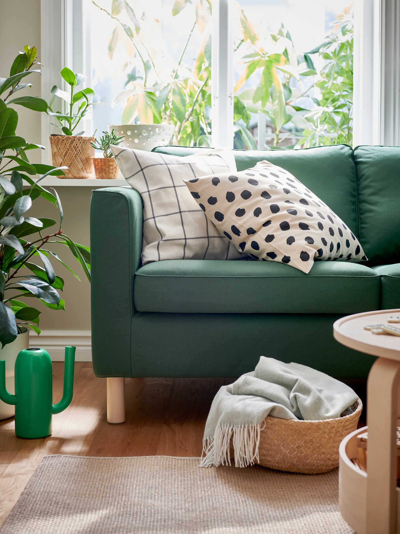 An ODDNY cushion cover in off-white with a black dot pattern on a green PÄRUP sofa