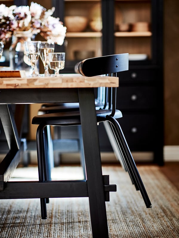 Dark yellow chairs with armrests hanging on an anthracite table, wooden floors, white pendant lamps.