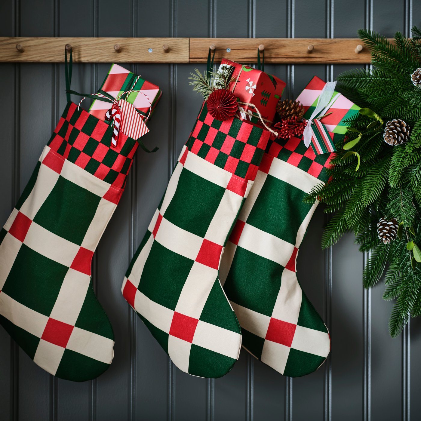 Drie VINTERFINT-kerstsokken met een opvallend groen-rood ruitjespatroon hangen aan rekken met knoppen.