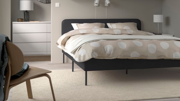 A Vissle dark grey SLATTUM upholstered bed frame in the bedroom