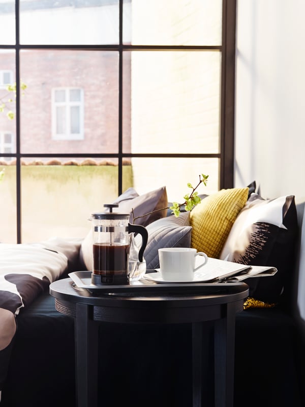 An UPPHETTA French press coffee/tea maker sits on a tray with an IKEA 365+ cup on a saucer in white to its right.