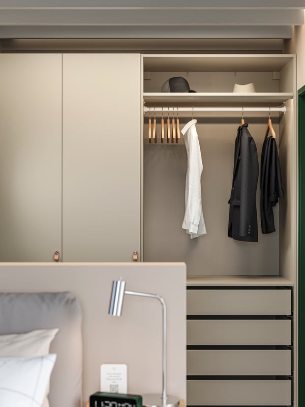 Hotelska soba s PAX/FORSAND garderoberom s otvorenim i zatvorenim prostorom za odlaganje, nekoliko komada odeće, šeširima, vešalicama i fiokama.