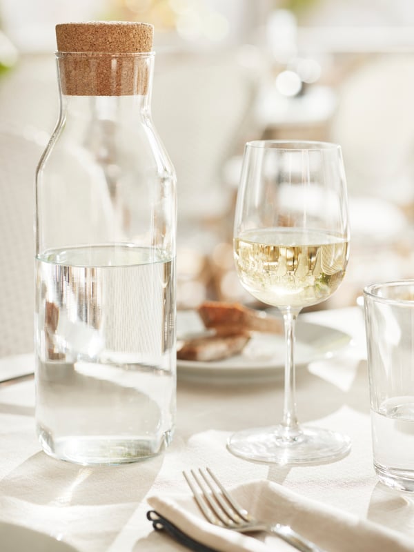 Un verra à vin est posé à côté d’une carafe IKEA 365+ en verre clair.