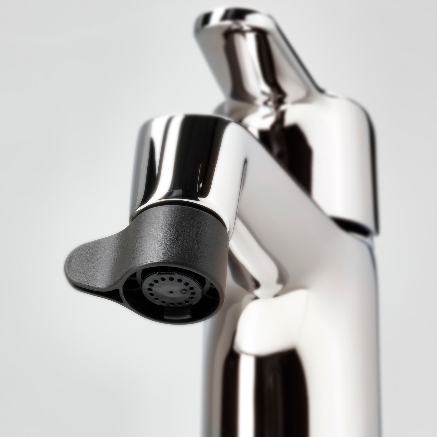 A close-up of an ÅBÄCKEN mist nozzle attached to a wash-basin mixer tap.