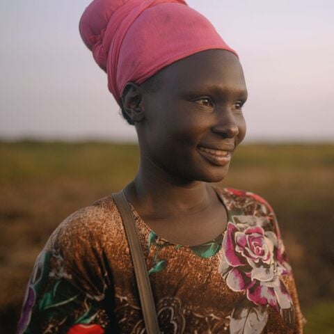 Potriat of a women standing on a open field smiling.