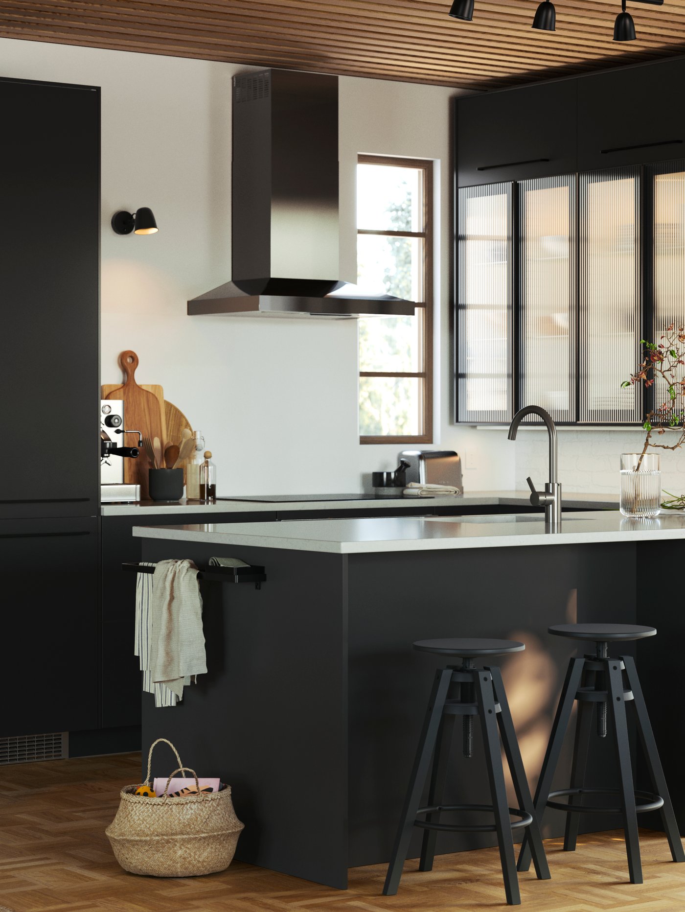 A kitchen with NICKEBO fronts, cabinets with HEJSTA glass doors in anthracite/reeded glass and DALFRED bar stools in black.