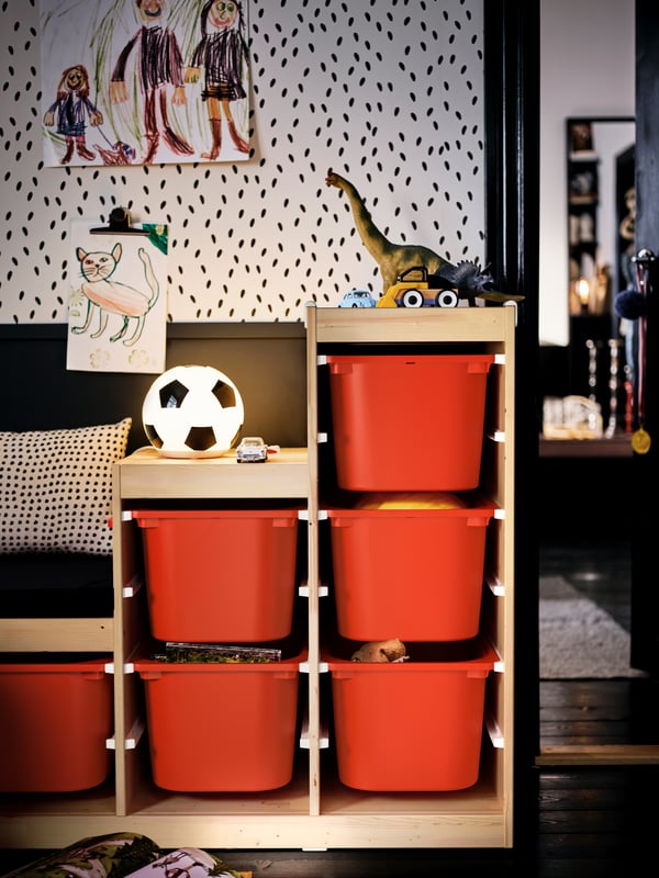 A wall with two units of TROFAST wall storage which hold TROFAST storage boxes, toys, books and a PELARBOJ LED table lamp.
