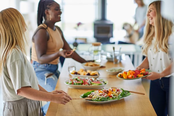 Un groupe de collaboratrices assises autour d’une table, partageant un repas commun. 