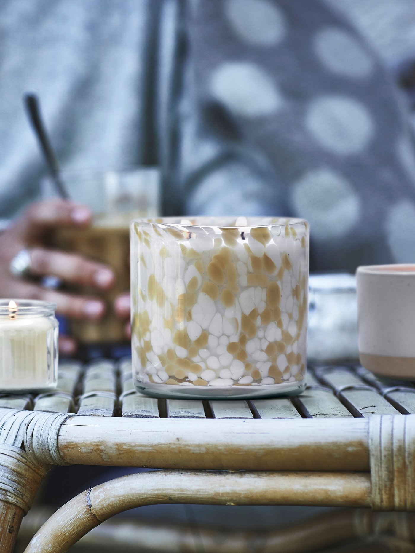 Three different kind of JÄMLIK scented candle on top of rattan outdoor table.