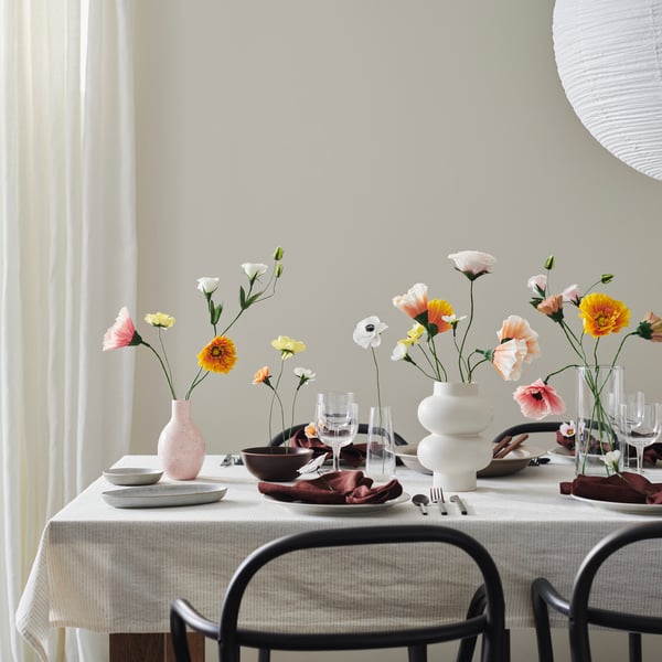 A table is decorated for a party with GULDSPETT artificial flowers, including flowers in a beige PÄRLHÄGG vase.