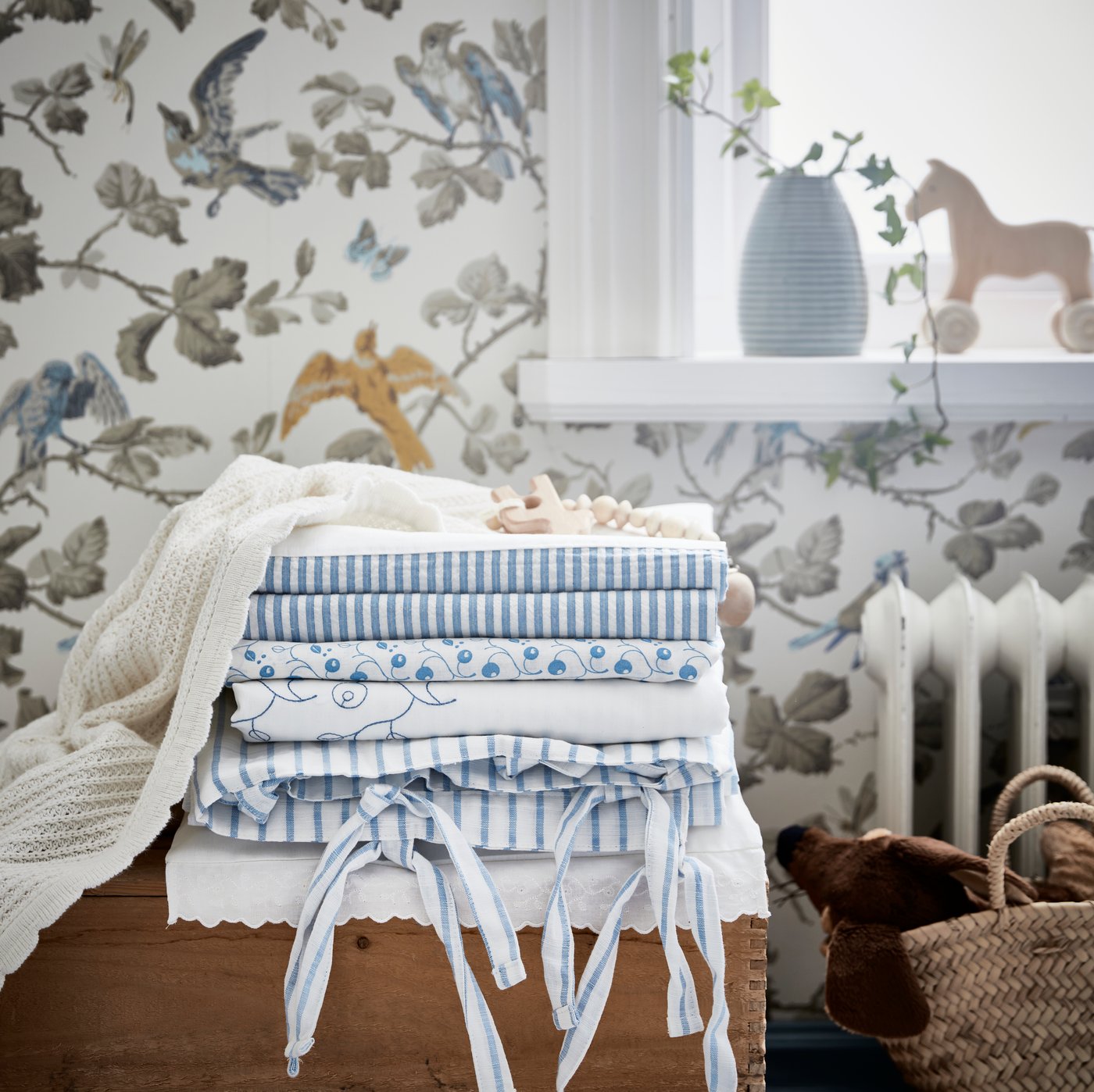 A stack of blue and white baby linens sitting in a nursery.