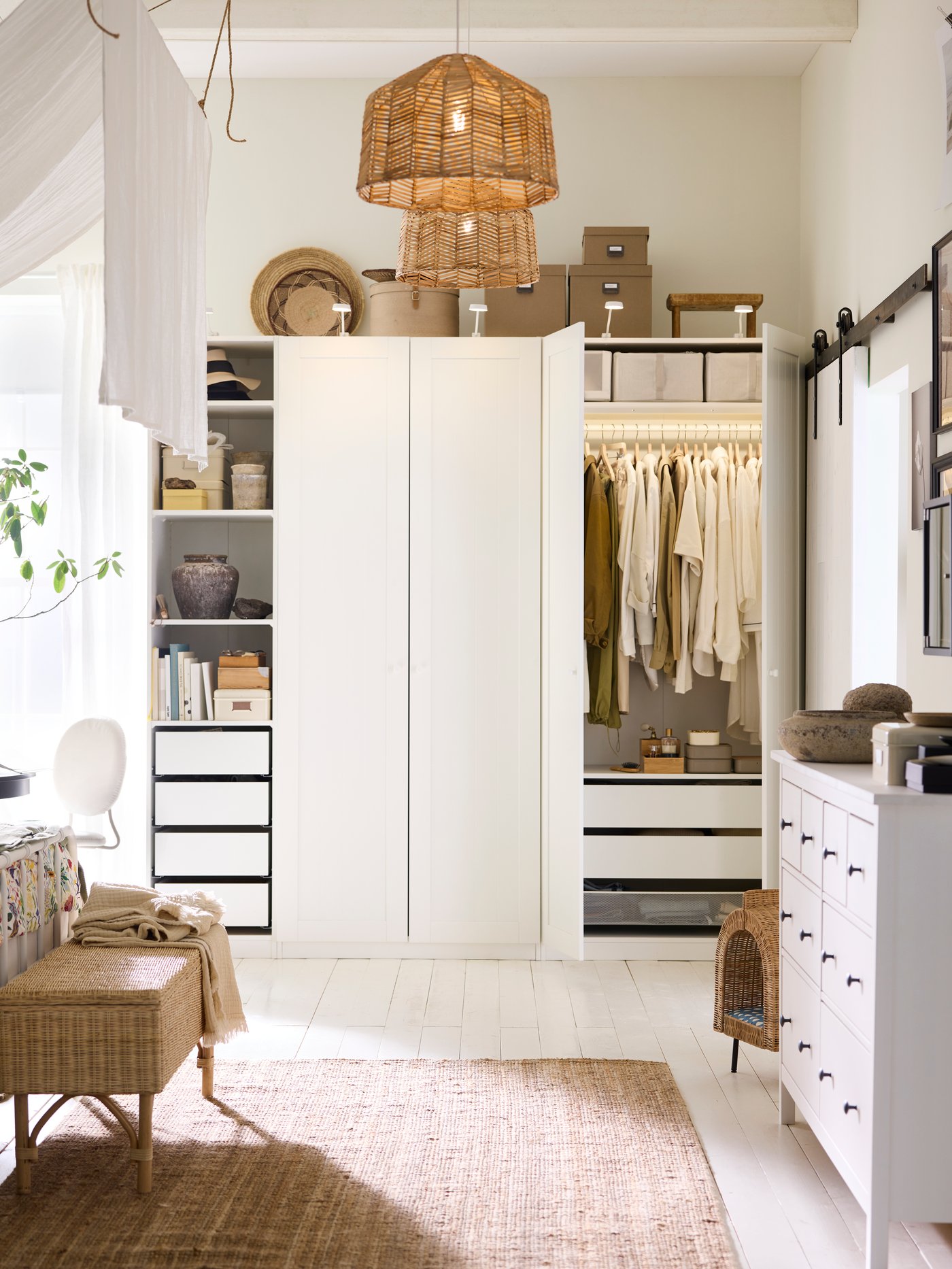 A white PAX/GULLABERG wardrobe combination in a white bedroom with two rattan KAPPERLAND pendant lampshades above it.