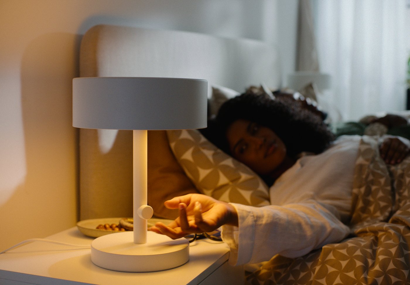 A white NYMÅNE table lamp in the bedroom