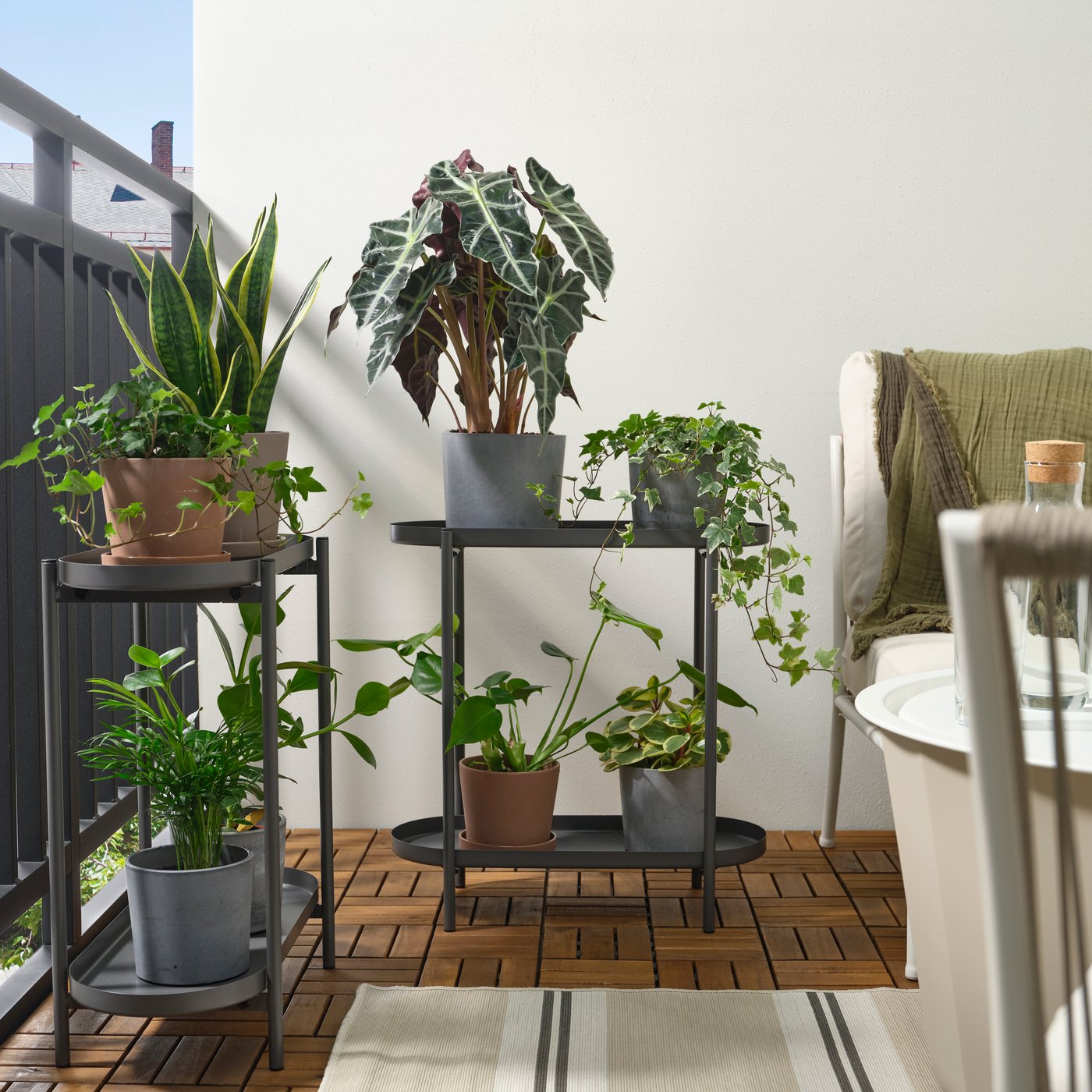 Pedestal para plantas OLIVBLAD para interior y exterior, colocado en un espacio al aire libre.