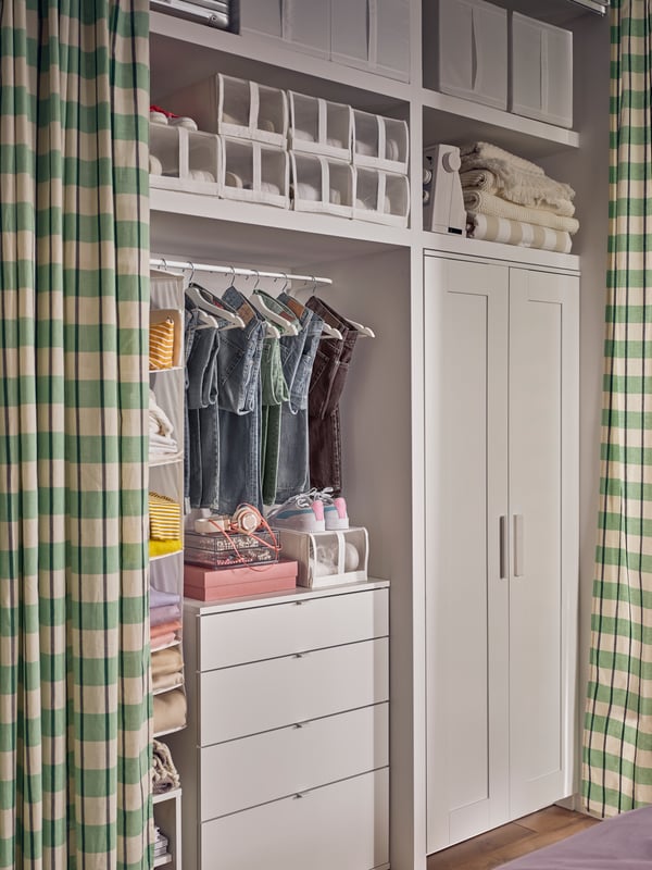 A VIHALS chest with 4 drawers beside a BRIMNES wardrobe. A hanging rail placed above it holds different coloured clothes.