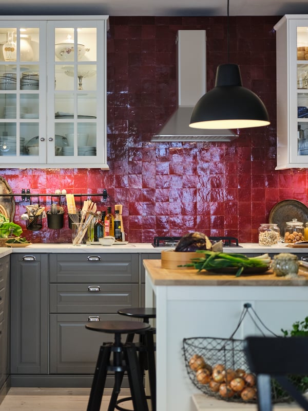 Une cuisine au carrelage rouge avec des rangements muraux blancs, des rangements METOD avec des aménagements intérieurs MAXIMERA, un îlot blanc avec un plan de travail en bois.
