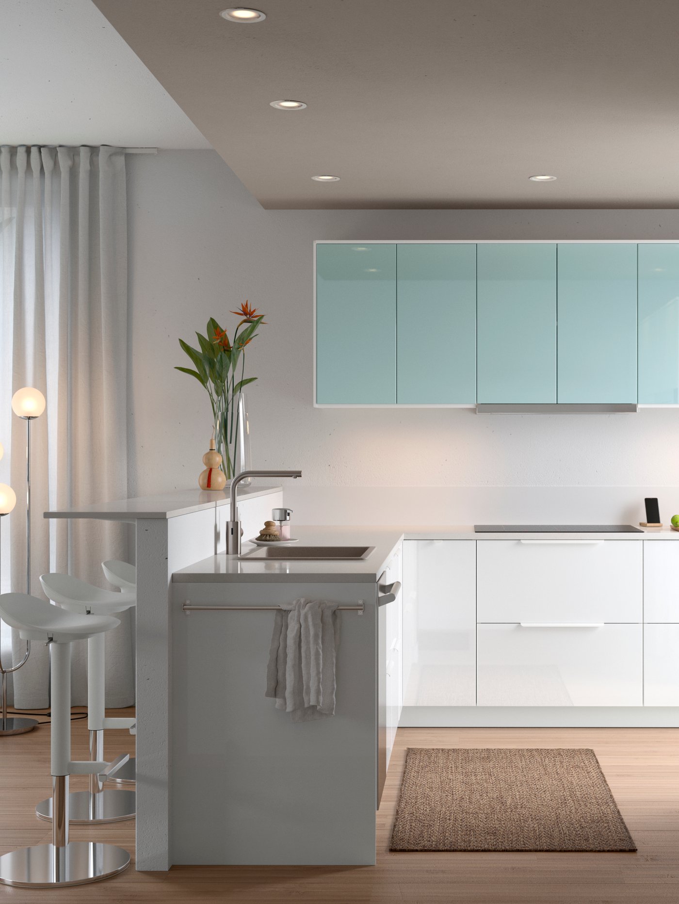 Una cocina abierta, grande y luminosa con frentes de puertas en turquesa y blanco y un florero con flores en la barra que hay sobre el fregadero.