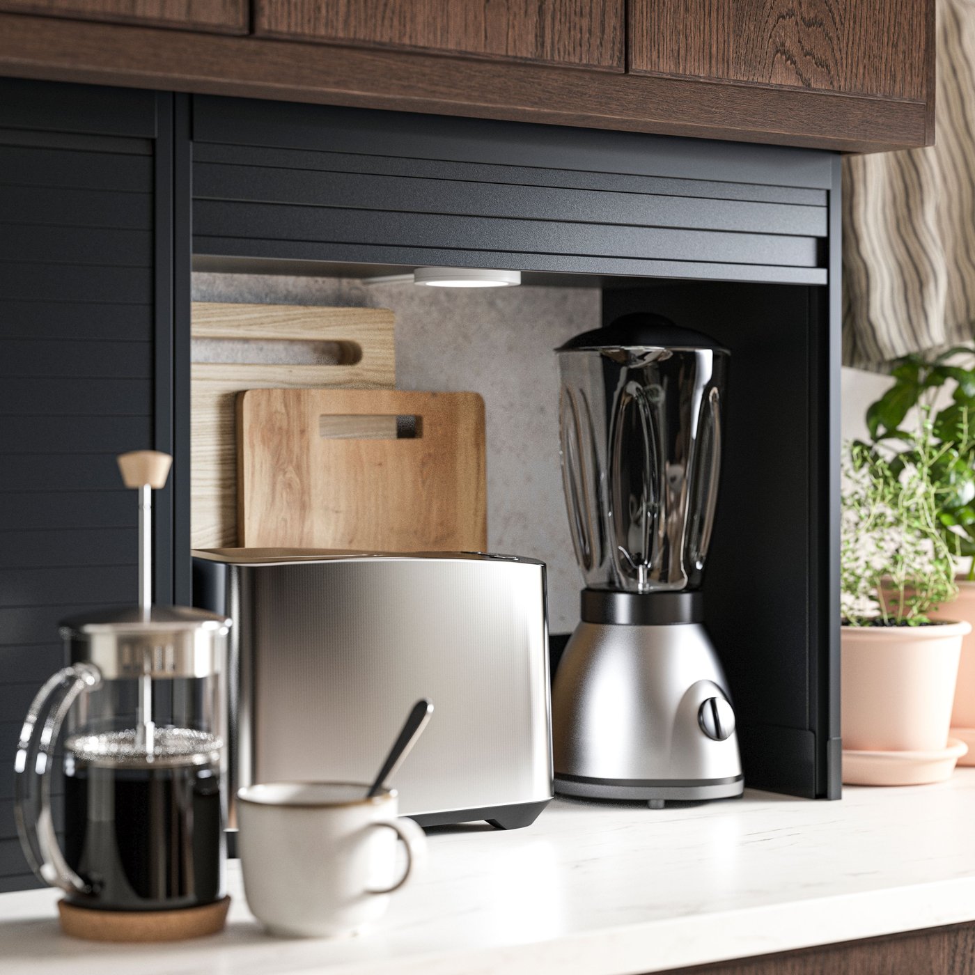 En öppen, svart TITTEBO-förvaring med jalusidörr för småelapparater, där en brödrost, en mixer och två skärbrädor syns inuti.
