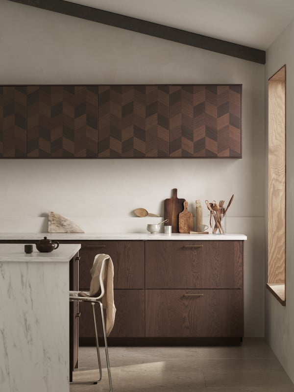 A kitchen with an island in marble effect a GLENN bar stool, brown SINARP drawers and brown patterned HASSLARP doors.