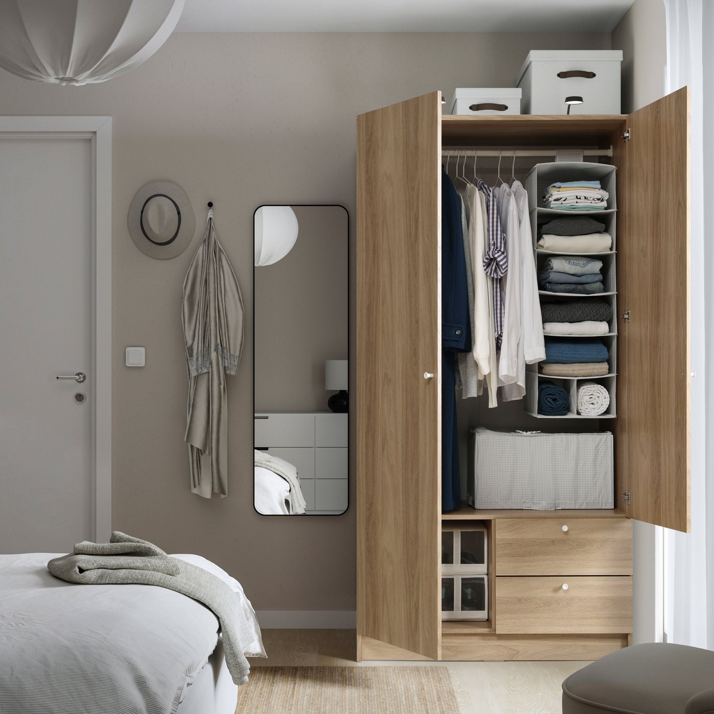 An oak-effect VILHATTEN wardrobe with 2 doors and drawers in a light bedroom with the doors open and a mirror on wall by it.