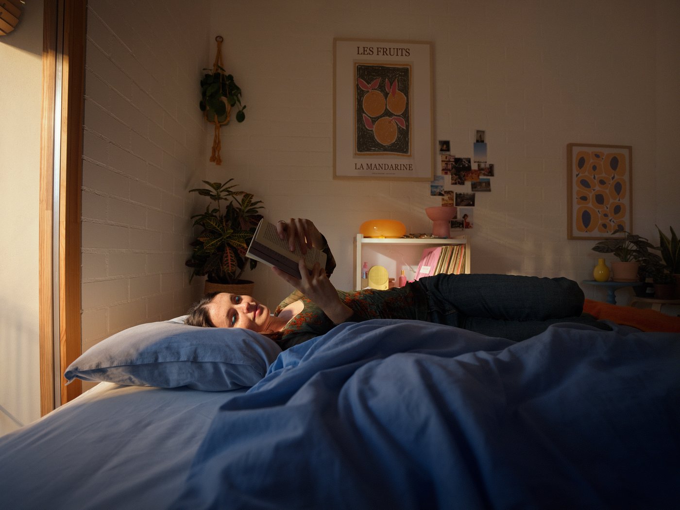 La lumière du matin inonde la chambre, où une femme lit tranquillement dans son lit.