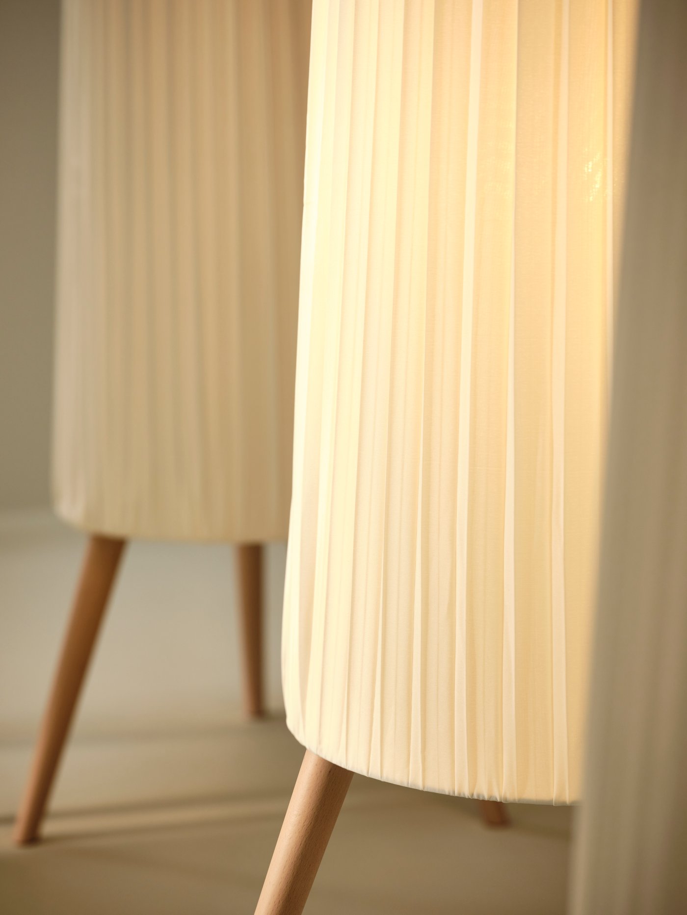 En närbild av ÖKENSAND golvlampa i bok och vitt.
