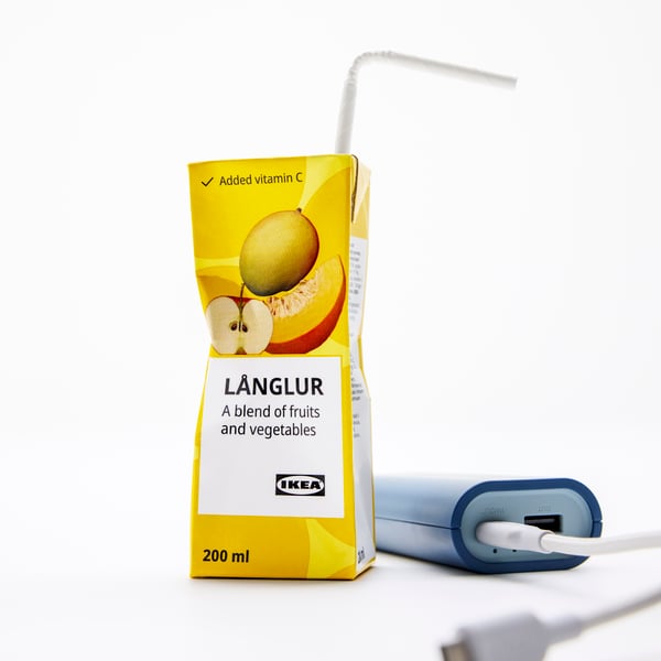 A pack of LÅNGLUR fruit and vegetable smoothie. Next to it, there’s a powerbank and mobile phone charger.