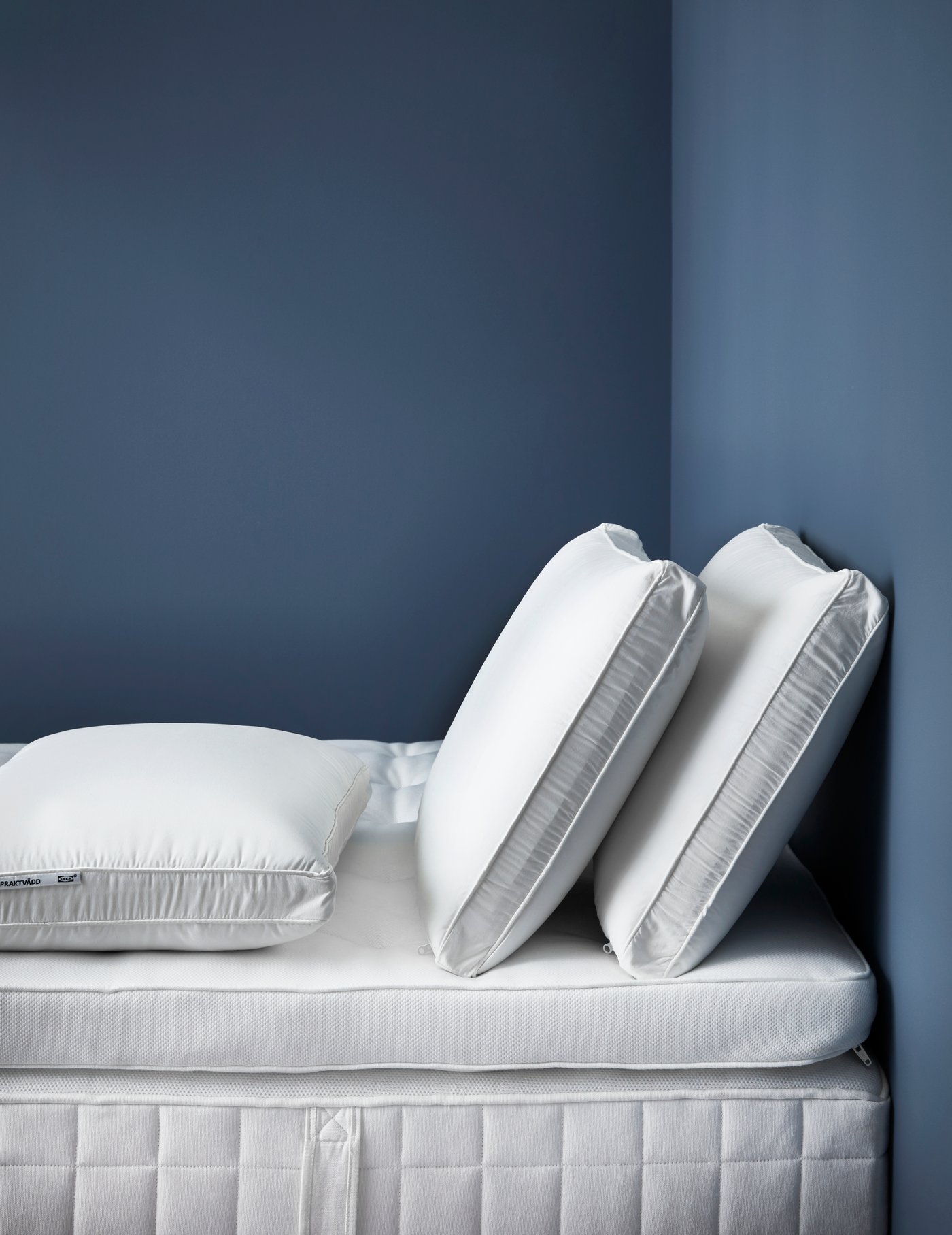 Una cama sin ropa de cama con dos colchones IKEA y encima dos almohadas GRÖNAMARAN.