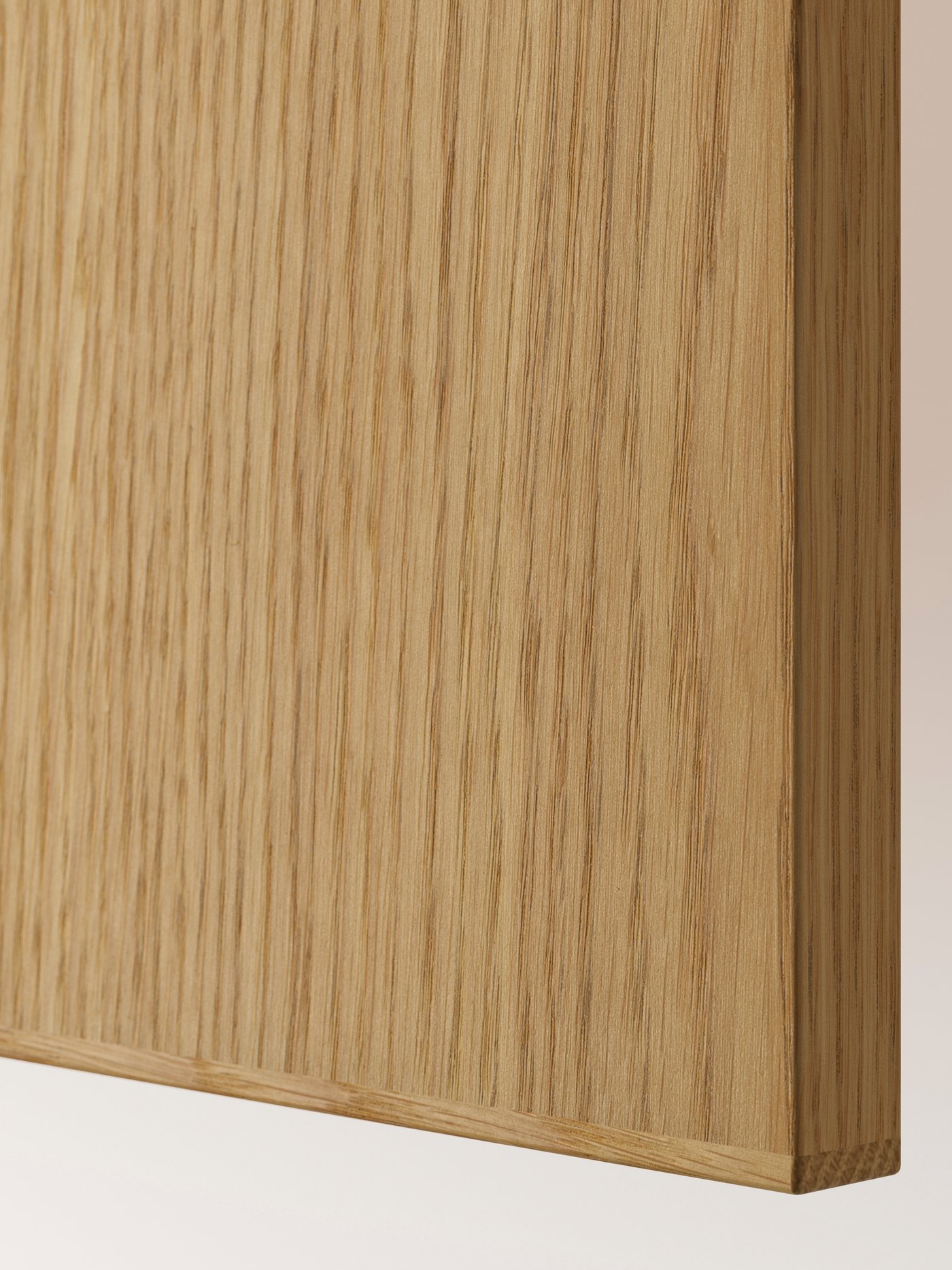 A closeup of a SINARP front in oak veneer, showing the smooth surface with the edge of solid oak wood.