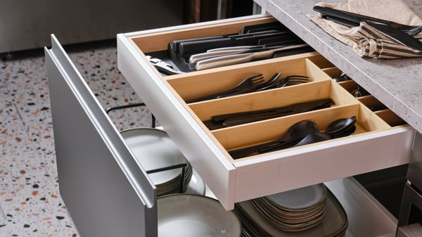 An open kitchen drawer with plates, and another kitchen drawer inside with a light bamboo UPPDATERA cutlery/knife rack in it.